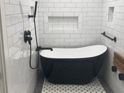 5 Reasons to Consider Master Bath Renovations in 2022 with Northshore Renovations and Contracting in Mandeville, LA. Image of a shower and bathtub in a bathroom recently renovated with beautiful white subway tile on the walls, a rail for ease of exiting the tub and a wooden flip table mounted to the wall next to tub