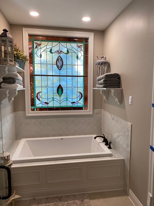 Planning A Bathroom Renovation Project | Northshore Renovations and Contracting of Covington, LA. Image of a beautiful bathroom with white bathtub, stained glass window, and towels in towel racks.